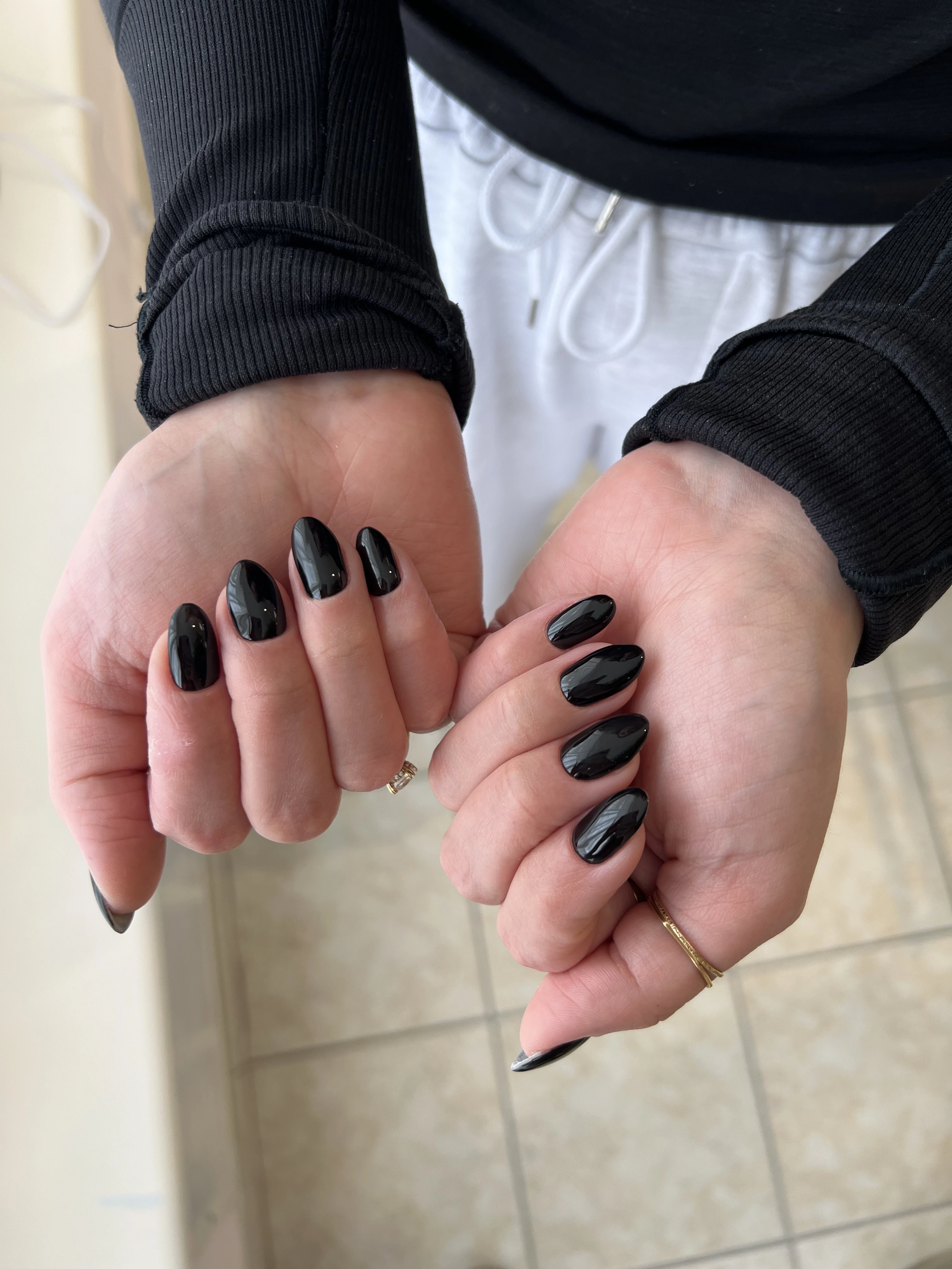 Mirror-gloss jet-black hard gel on oval nails with gold rings, a sleek manicure done at My Beauty Space in Mississauga.