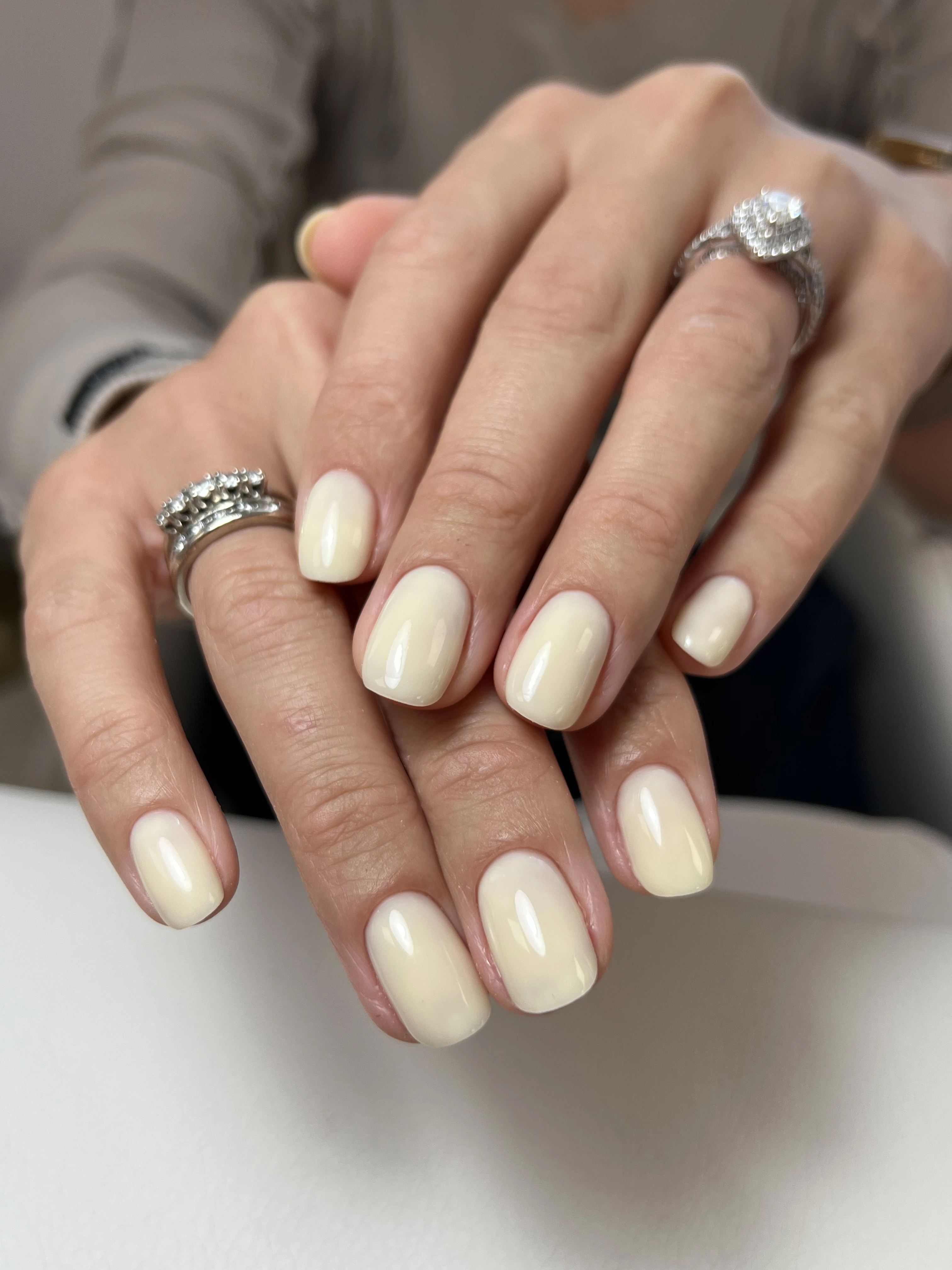 Glossy buttercream gel polish on short squoval nails with diamond rings, a refined manicure from My Beauty Space in Mississauga.