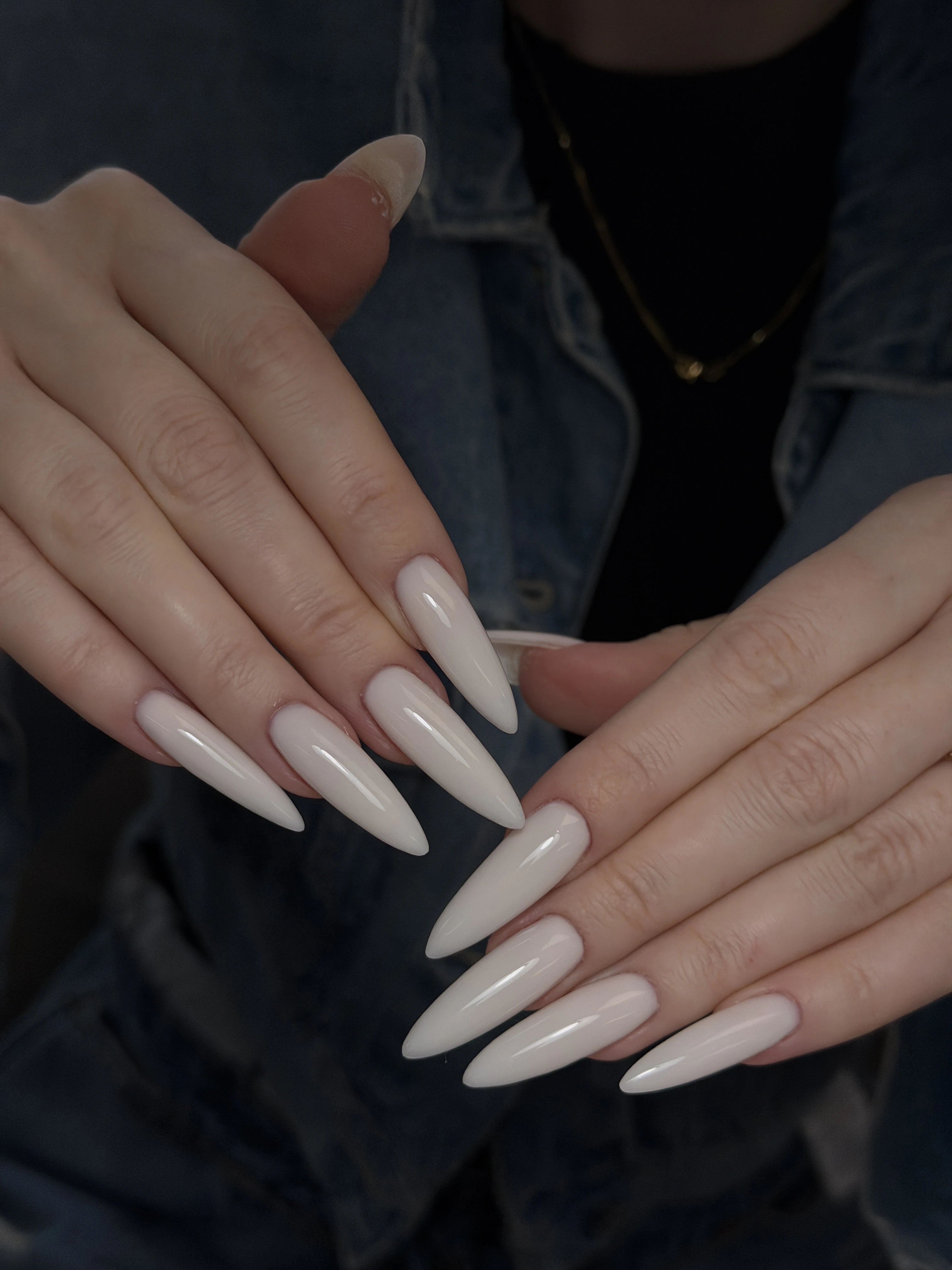 Extra-long stiletto Gel-X at My Beauty Space in pearly off-white high gloss, hands layered over a denim jacket.