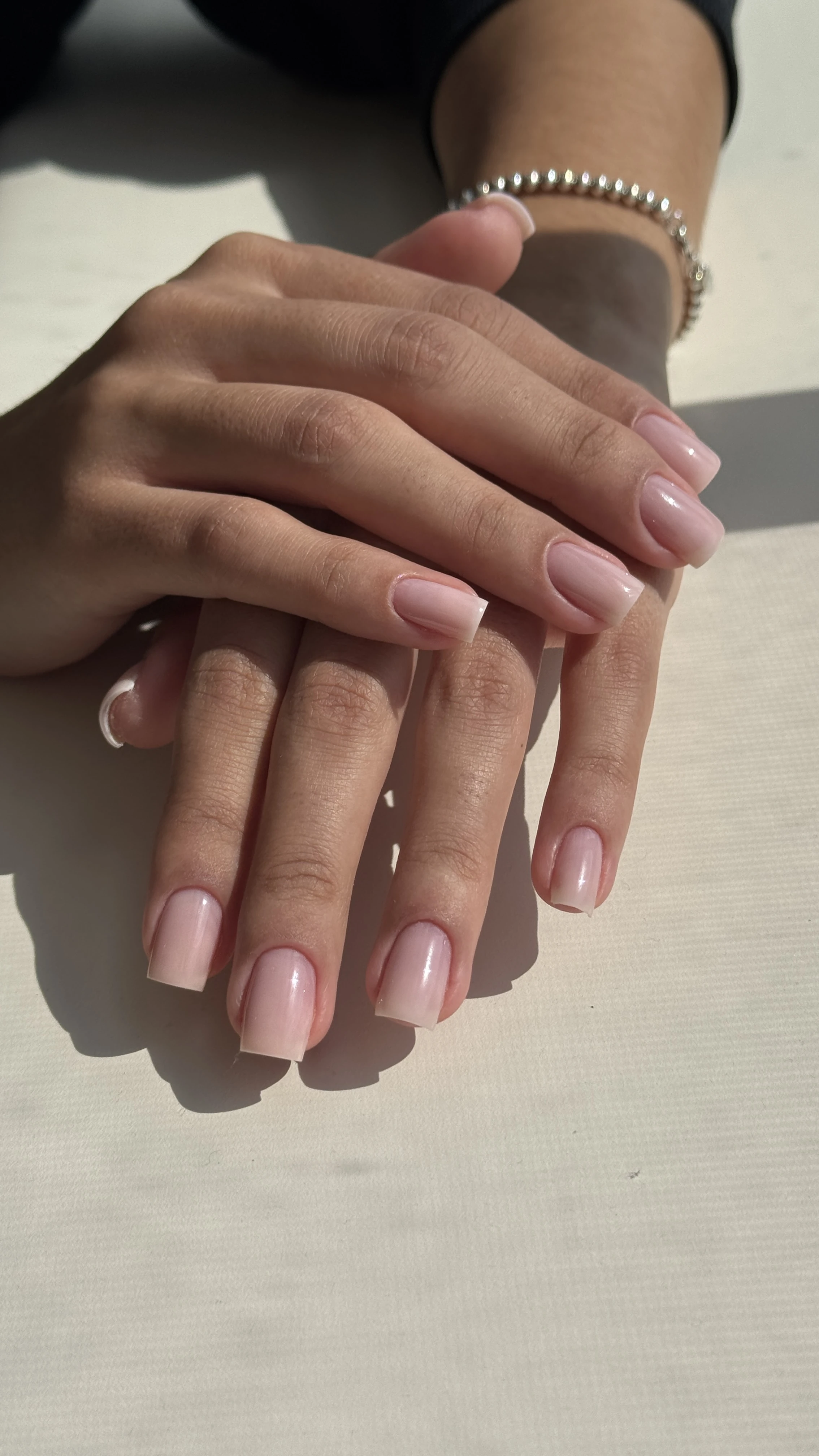 Translucent milky-pink gel polish on square nails with a beaded silver bracelet, finished at My Beauty Space in Mississauga.